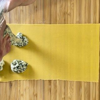 Una persona sta preparando i ravioli su un tagliere di legno.