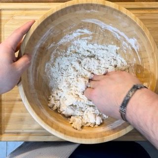 Una persona sta mescolando la farina in una ciotola di legno