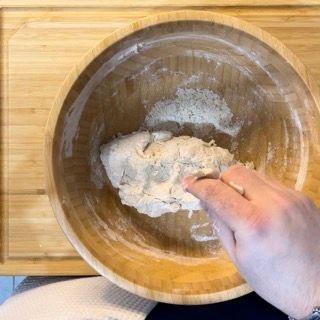 Una persona sta mescolando la farina in una ciotola di legno