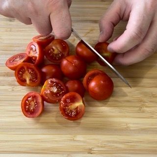 Una persona sta tagliando i pomodori su un tagliere