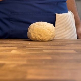 Una palla di pasta è appoggiata su un tavolo di legno.