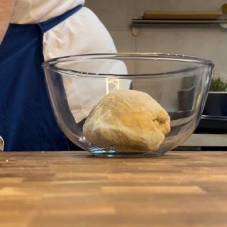 Una ciotola di vetro con dentro una palla di pasta