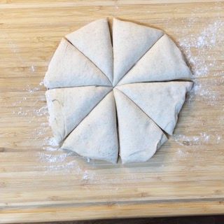 Un cerchio di pasta tagliato a triangoli su un tagliere di legno