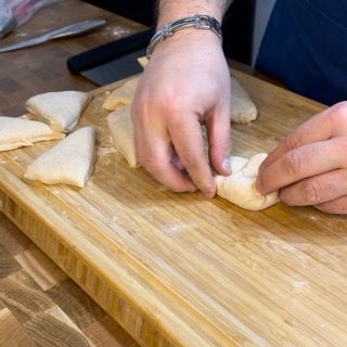 Una persona sta impastando la pasta su un tagliere di legno