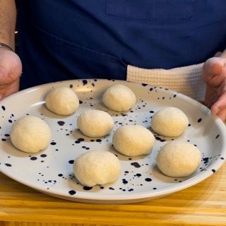 Una persona tiene in mano un piatto di palline di pasta