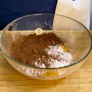 Una ciotola di vetro piena di cacao in polvere e farina