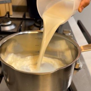 Una persona sta versando del liquido in una pentola sul fornello