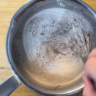 Una persona sta mescolando una pentola di liquido con una frusta