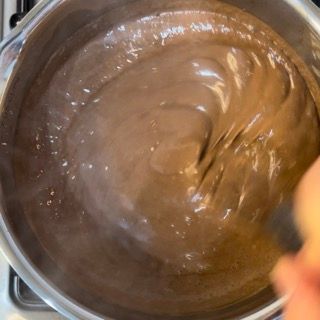 Una persona sta mescolando un liquido marrone in una pentola