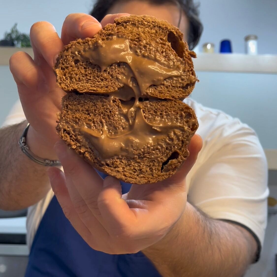 Un uomo tiene in mano un pezzo di pane con sopra della salsa al cioccolato