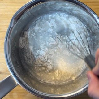 Una persona sta sbattendo una pentola di liquido con una frusta.