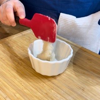 Una persona sta mescolando qualcosa in una piccola ciotola con una spatola