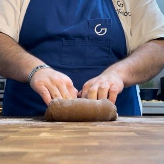 Una persona che indossa un grembiule blu con la lettera g sopra