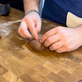 Una persona sta impastando la pasta su un tagliere di legno