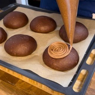 Una persona sta spalmando la glassa al cioccolato su un mucchio di palline di cioccolato