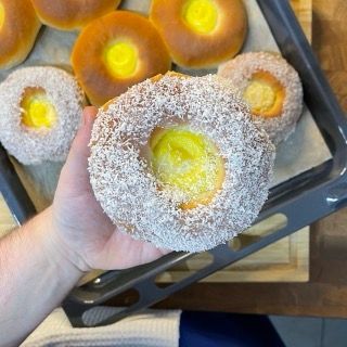 Una persona tiene in mano una ciambella ricoperta di zucchero a velo