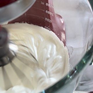 Un mixer sta mescolando un liquido bianco in un misurino.