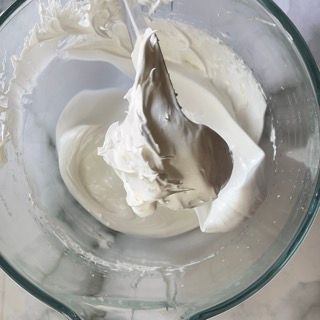 Una ciotola di vetro piena di glassa bianca con un cucchiaio dentro.