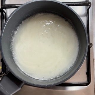 Una pentola piena di liquido bianco è posta sopra un fornello.