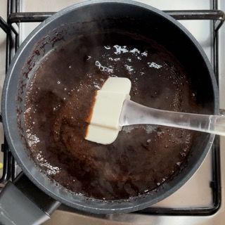 Una pentola di liquido marrone con una spatola dentro