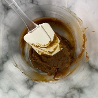 Una spatola è in una ciotola di liquido marrone