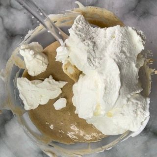 La panna montata viene aggiunta a un impasto in una ciotola di vetro