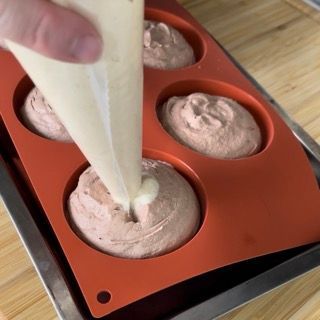 Una persona sta versando la glassa in uno stampo in silicone