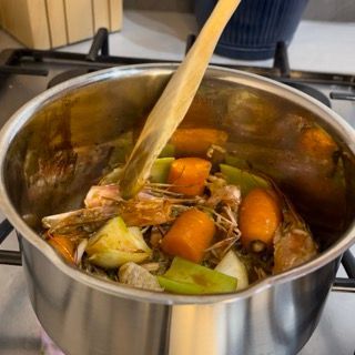 Una pentola di cibo viene mescolata con un cucchiaio di legno