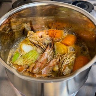 Una pentola di gamberi e verdure sta cuocendo sul fornello.