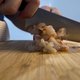 Una persona sta tagliando i gamberi su un tagliere