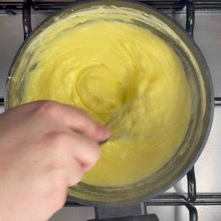 Una persona sta mescolando un liquido giallo in una pentola sul fornello.