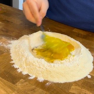 Una persona sta mescolando gli ingredienti in un mucchio di farina