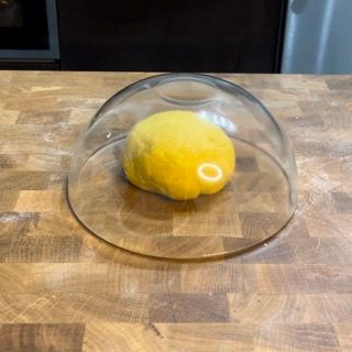Una palla gialla è sotto una cupola di vetro su un tavolo di legno