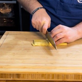 Una persona sta tagliando un pezzo di cibo su un tagliere