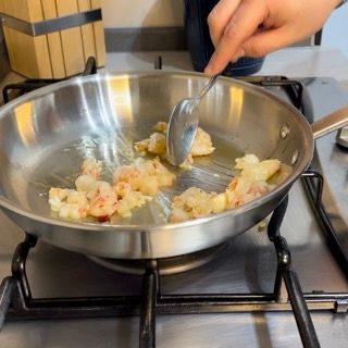 Una persona sta mescolando i gamberi in una padella con un cucchiaio