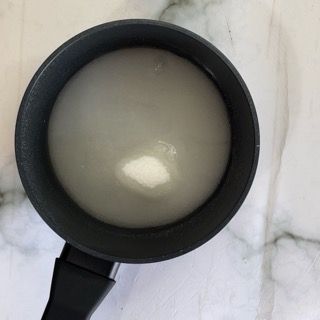 Su un tavolo c'è una pentola nera piena di liquido bianco.