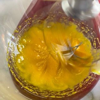 Una persona sta mescolando un liquido giallo in una ciotola con una frusta.