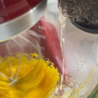 Una persona versa acqua in un frullatore pieno di liquido giallo.