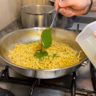 Una persona sta versando del liquido in una padella di noodles