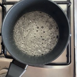 Una padella piena di liquido è posta sopra un fornello.