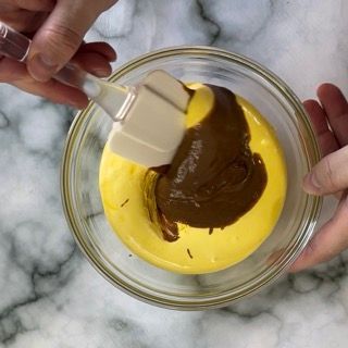 Una persona sta mescolando un liquido giallo con del cioccolato in una ciotola di vetro