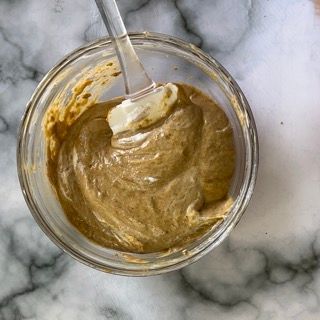 Una ciotola di salsa con un cucchiaio dentro su un tavolo.