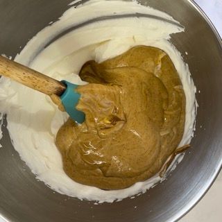 Una ciotola di panna montata con un cucchiaio di legno dentro
