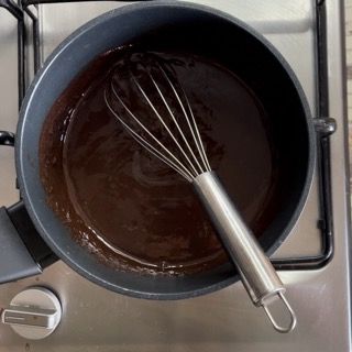 Una pentola di salsa al cioccolato con una frusta dentro