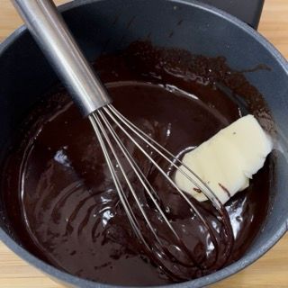 Una frusta è in una pentola di salsa al cioccolato