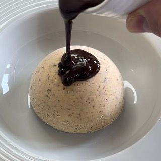 Una persona versa la salsa al cioccolato su un dessert in una ciotola