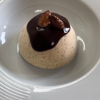 Un piatto bianco sormontato da un dessert con salsa al cioccolato e noci.