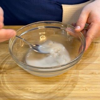 Una persona tiene in mano una ciotola di vetro con un cucchiaio dentro