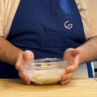 Un uomo con un grembiule blu tiene in mano una ciotola di cibo