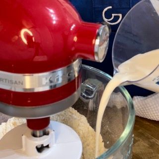 Un mixer rosso KitchenAid versa del liquido in una ciotola di vetro